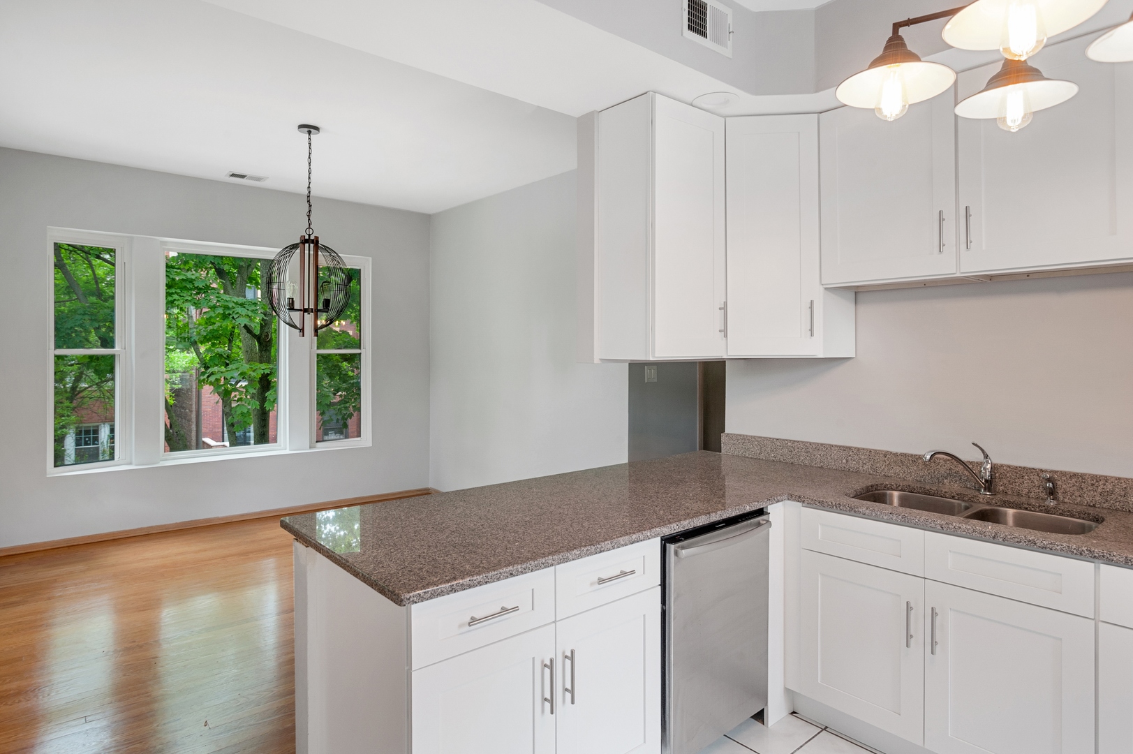 5556 North Wayne Avenue Chicago, IL 60640 - Photo 32 of 37 a kitchen with stainless steel appliances granite countertop a sink a window and white cabinets