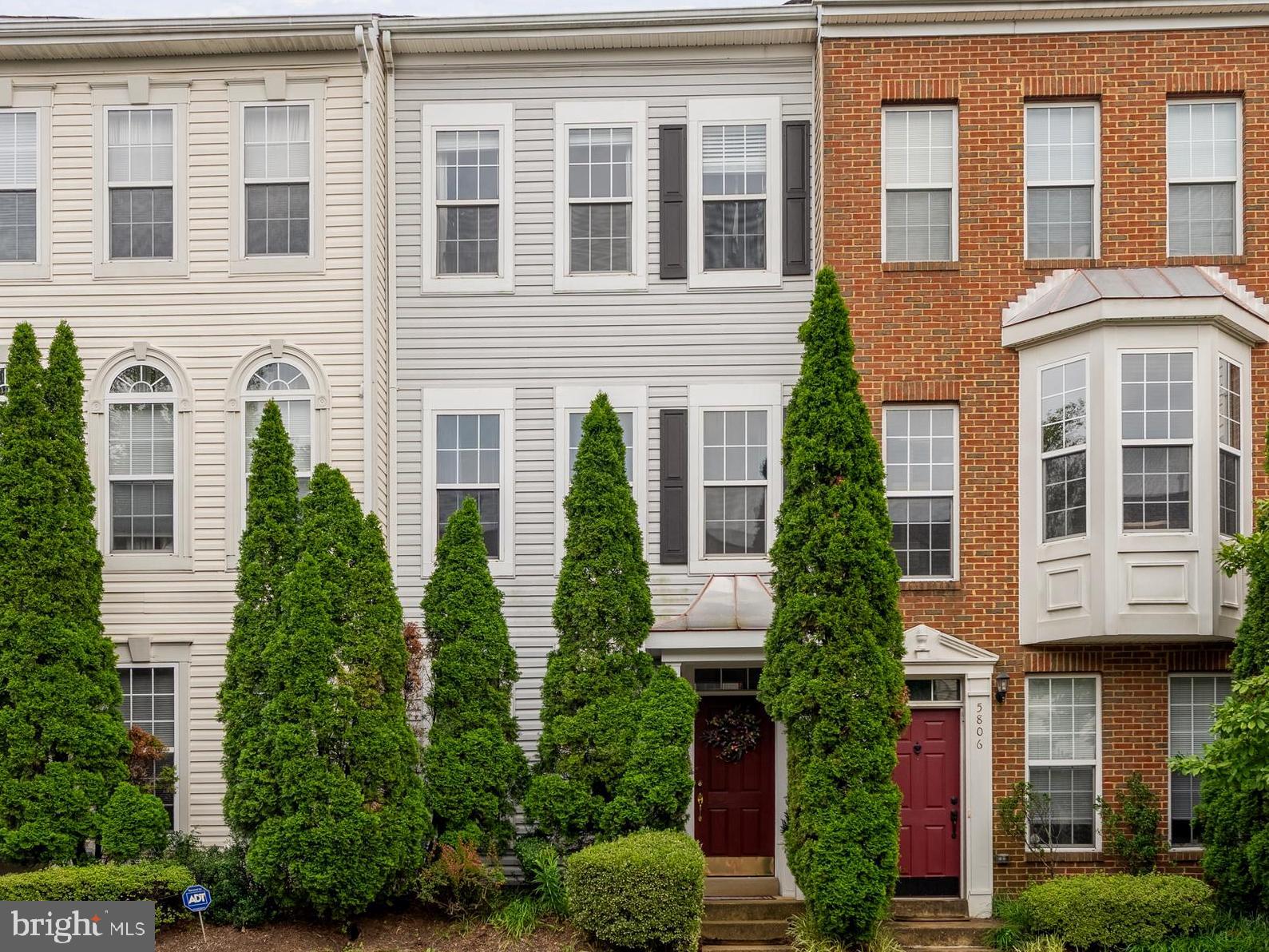 a front view of a residential apartment building with a yard and potted plants