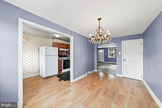 a dining room with chandelier and wooden floor