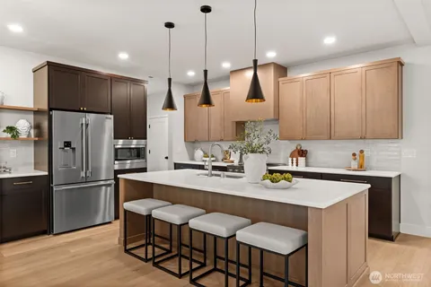 a kitchen with kitchen island a refrigerator a sink and a stove