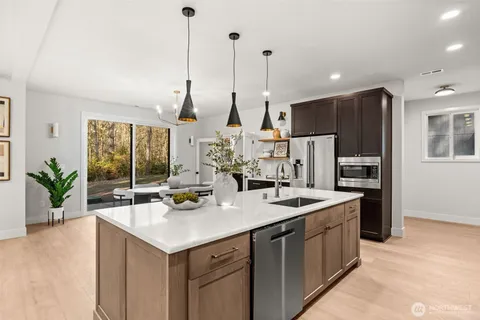 a kitchen with stainless steel appliances kitchen island granite countertop a sink and a refrigerator