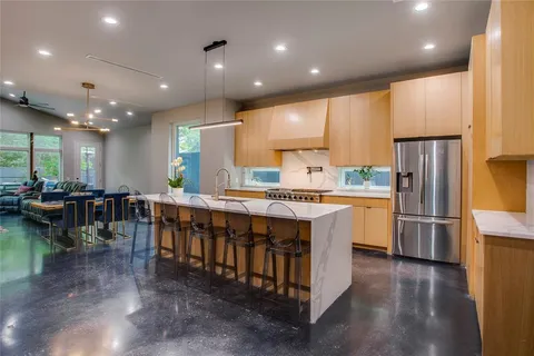 a large kitchen with stainless steel appliances a large counter top a stove a chimney a sink and a refrigerator