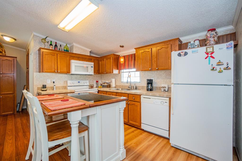 10303 Burnt Store Road, Unit 203 Punta Gorda, FL 33950 - Photo 5 of 41 a kitchen with a refrigerator a sink dishwasher and a stove with wooden floor