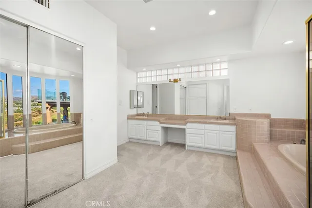 a bathroom with a sink double vanity granite tub and a mirror