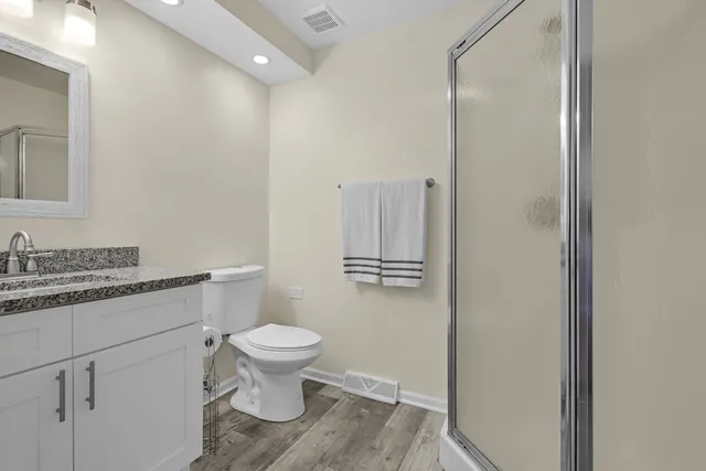 a bathroom with a granite countertop toilet a sink and a mirror