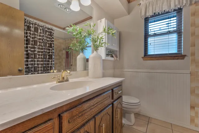 a bathroom with a granite countertop sink a toilet and mirror