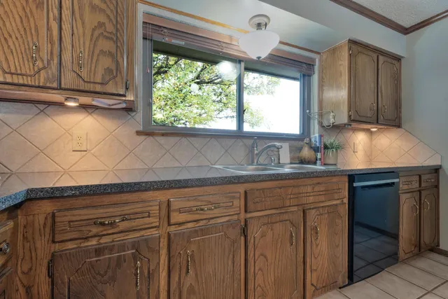 a kitchen with stainless steel appliances granite countertop a sink a stove and a wooden cabinets