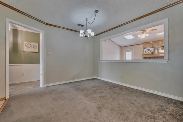 en empty room with windows and a chandelier fan