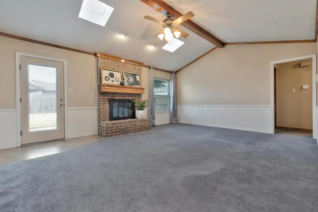 a view of an empty room with a fireplace and a window