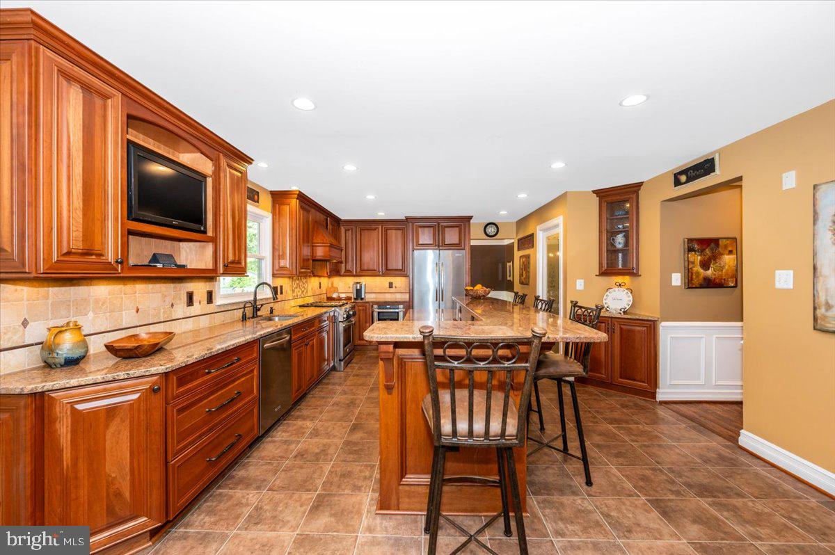 8412 Dasher Court Gaithersburg, MD 20882 - Photo 11 of 83 a kitchen with stainless steel appliances granite countertop wooden cabinets a sink a stove a dining table and chairs