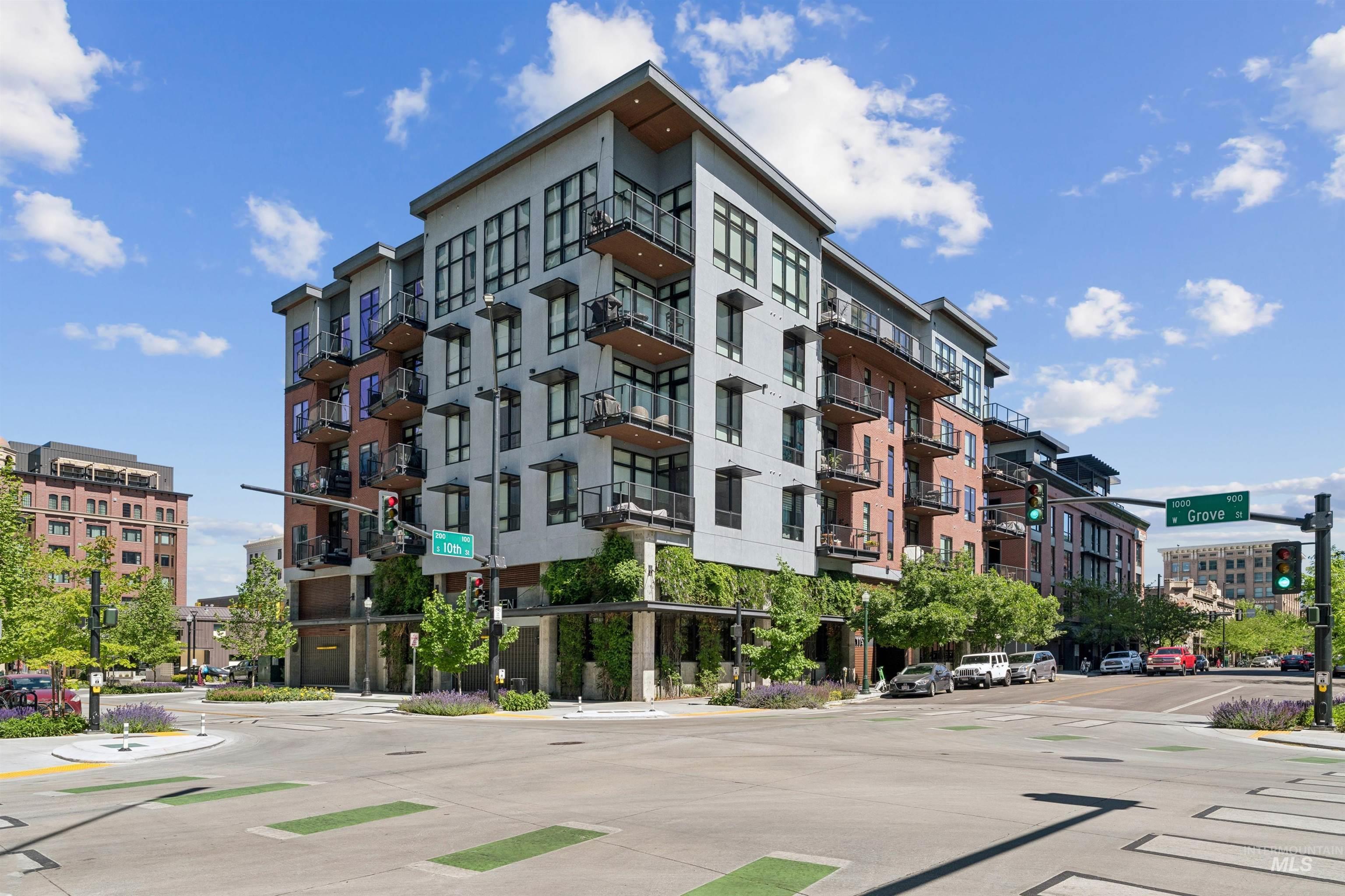 119 South 10th Street, Unit 307 Boise, ID 83702 - Photo 2 of 47 Modern multi-story building featuring a gray and brick facade, individual balconies with dark railings, and ground-level greenery