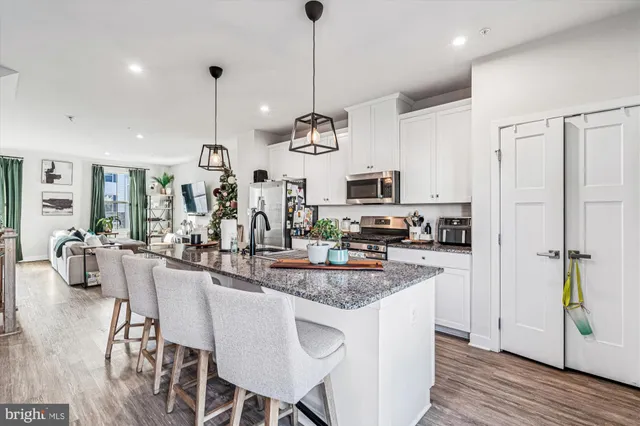 a kitchen with stainless steel appliances granite countertop a stove a refrigerator a kitchen island a sink cabinets and wooden floor