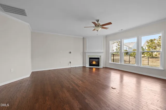 a view of empty room with wooden floor and ceiling fan
