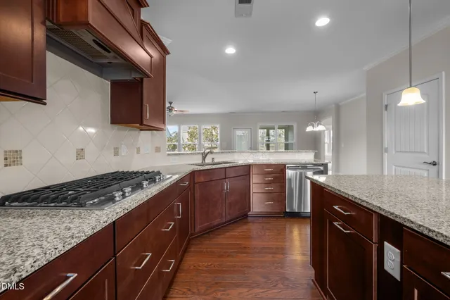 a kitchen with stainless steel appliances granite countertop a refrigerator a oven and a sink with wooden floor