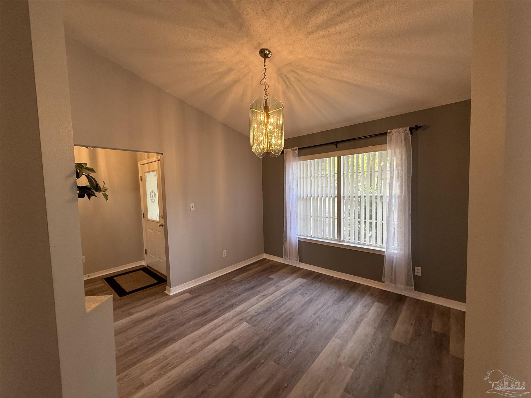 5700 Charmonte Way Milton, FL 32583 - Photo 15 of 29 a view of a room with wooden floor chandelier and windows