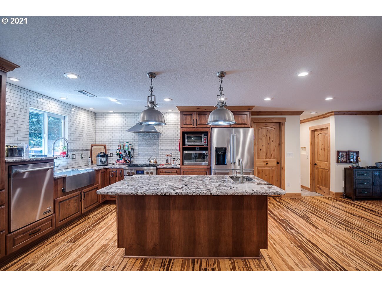 22255 Southeast Ridgeview Drive Damascus, OR 97089 - Photo 5 of 32 a large kitchen with stainless steel appliances a large counter top a stove and a wooden floors