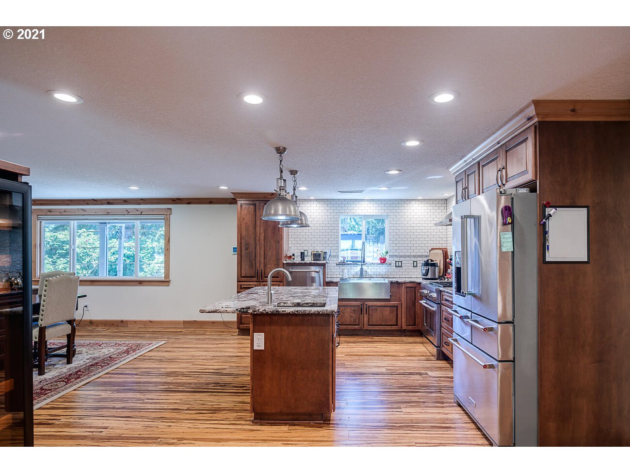 22255 Southeast Ridgeview Drive Damascus, OR 97089 - Photo 6 of 32 a kitchen with stainless steel appliances granite countertop a refrigerator a sink dishwasher a stove and a dining table with wooden floor