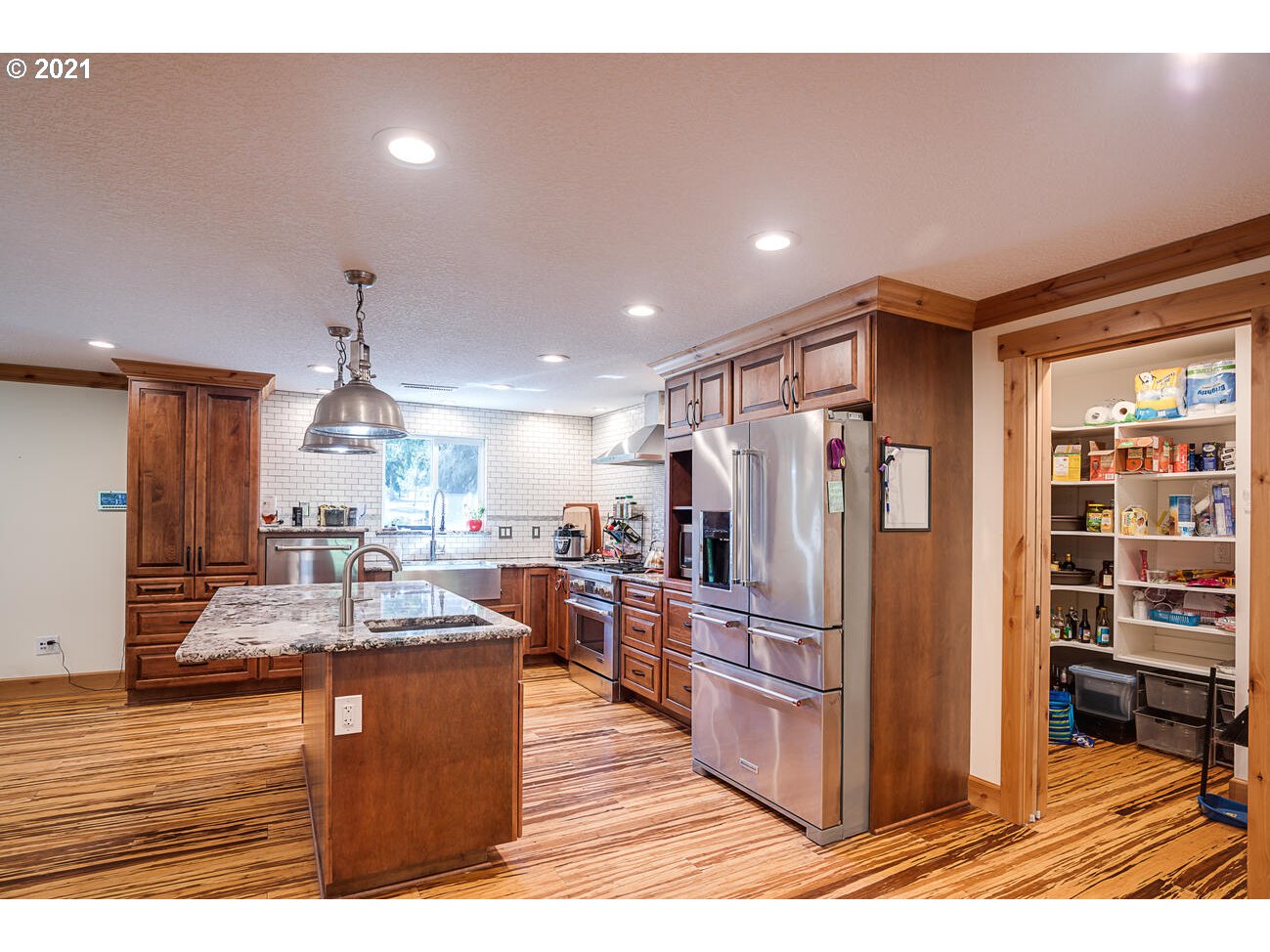 22255 Southeast Ridgeview Drive Damascus, OR 97089 - Photo 7 of 32 a kitchen with stainless steel appliances granite countertop a refrigerator and a stove top oven with wooden floor