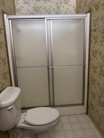 a white toilet sitting next to a shower