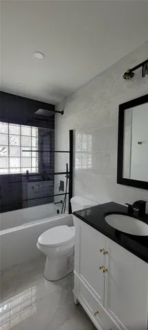 a bathroom with a granite countertop sink a toilet a mirror and bathtub