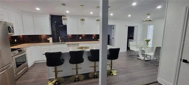 a kitchen with stainless steel appliances kitchen island granite countertop a stove a sink and a refrigerator