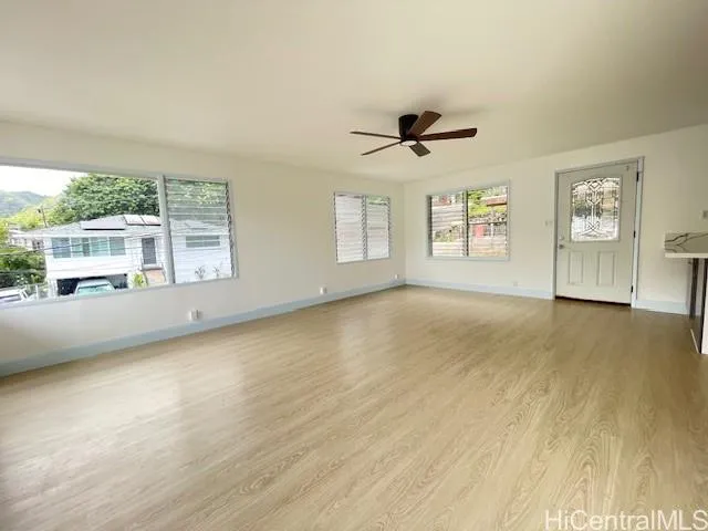a view of an empty room with a window and wooden floor