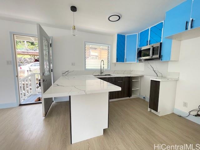 1565 Moani Street Honolulu, HI 96819 - Photo 5 of 22 a kitchen with kitchen island a stove a sink a microwave and wooden cabinets