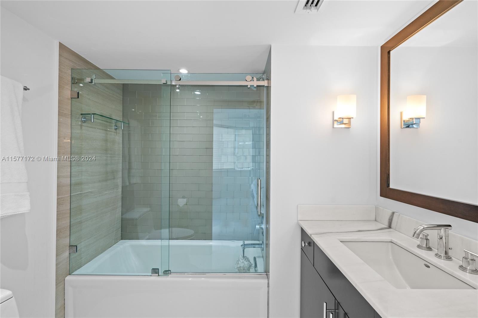 1621 Bay Road, Unit 702 Miami Beach, FL 33139 - Photo 19 of 32 a bathroom with a bathtub sink vanity and mirror