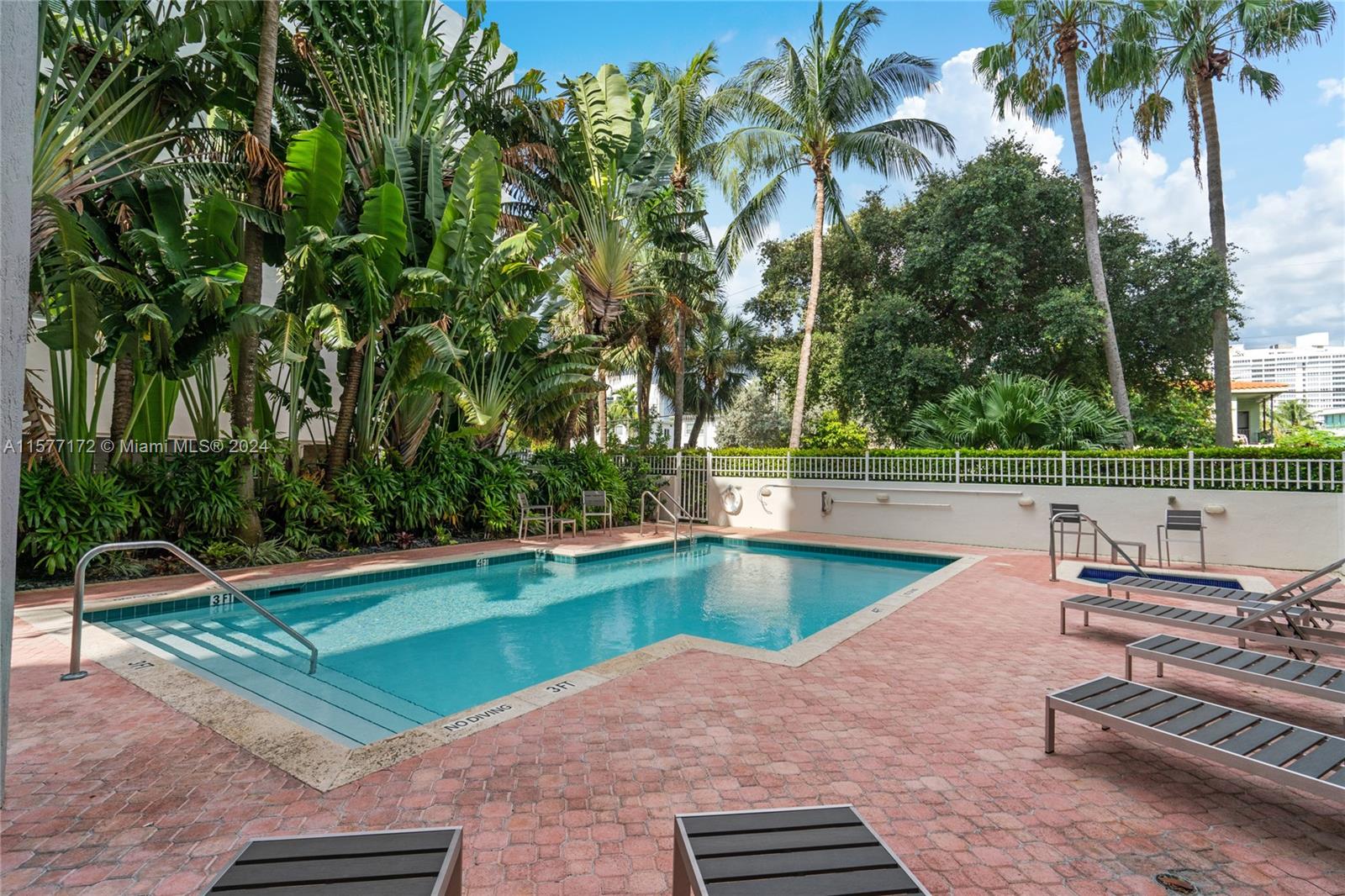 1621 Bay Road, Unit 702 Miami Beach, FL 33139 - Photo 30 of 32 a view of a swimming pool with a yard and palm trees