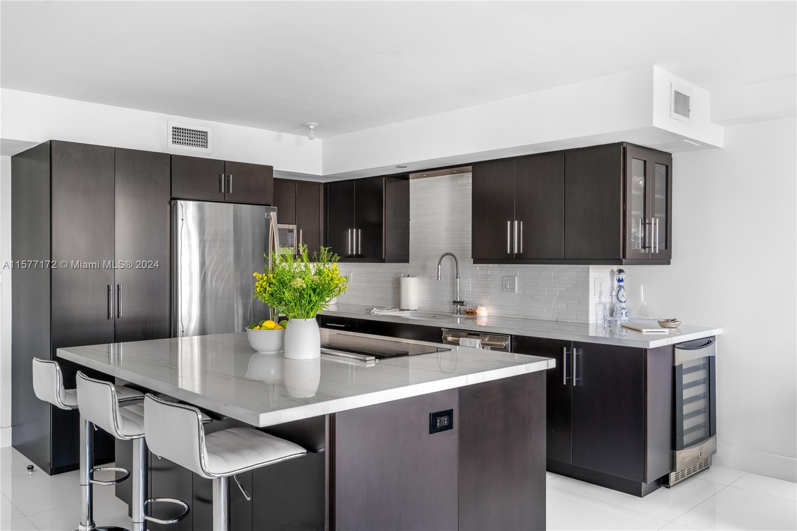 1621 Bay Road, Unit 702 Miami Beach, FL 33139 - Photo 6 of 32 a kitchen with stainless steel appliances a sink a microwave a refrigerator and chairs