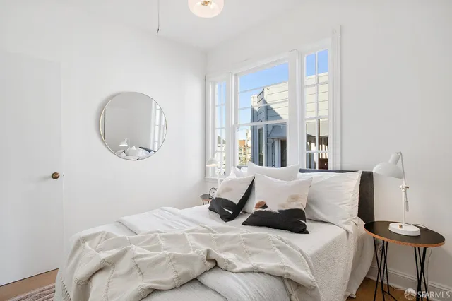 a bedroom with a bed and a large mirror next to a window