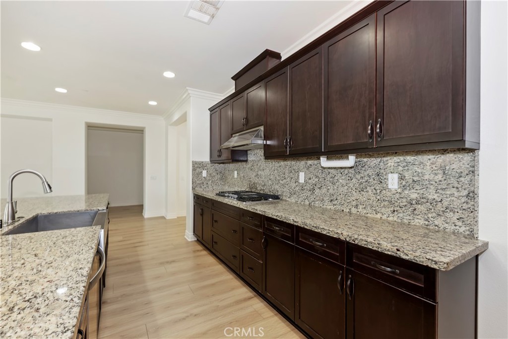 6336 Sloane Court Rancho Cucamonga, CA 91739 - Photo 22 of 69 a kitchen with granite countertop wooden cabinets a stove top oven a sink and dishwasher