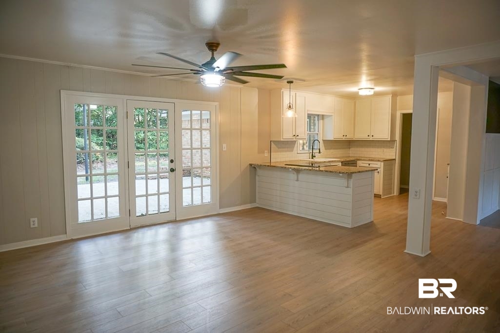 6205 Zeigler Boulevard Mobile, AL 36608 - Photo 2 of 17 Kitchen featuring a peninsula, wood finished floors, white cabinetry, ceiling fan, and a breakfast bar