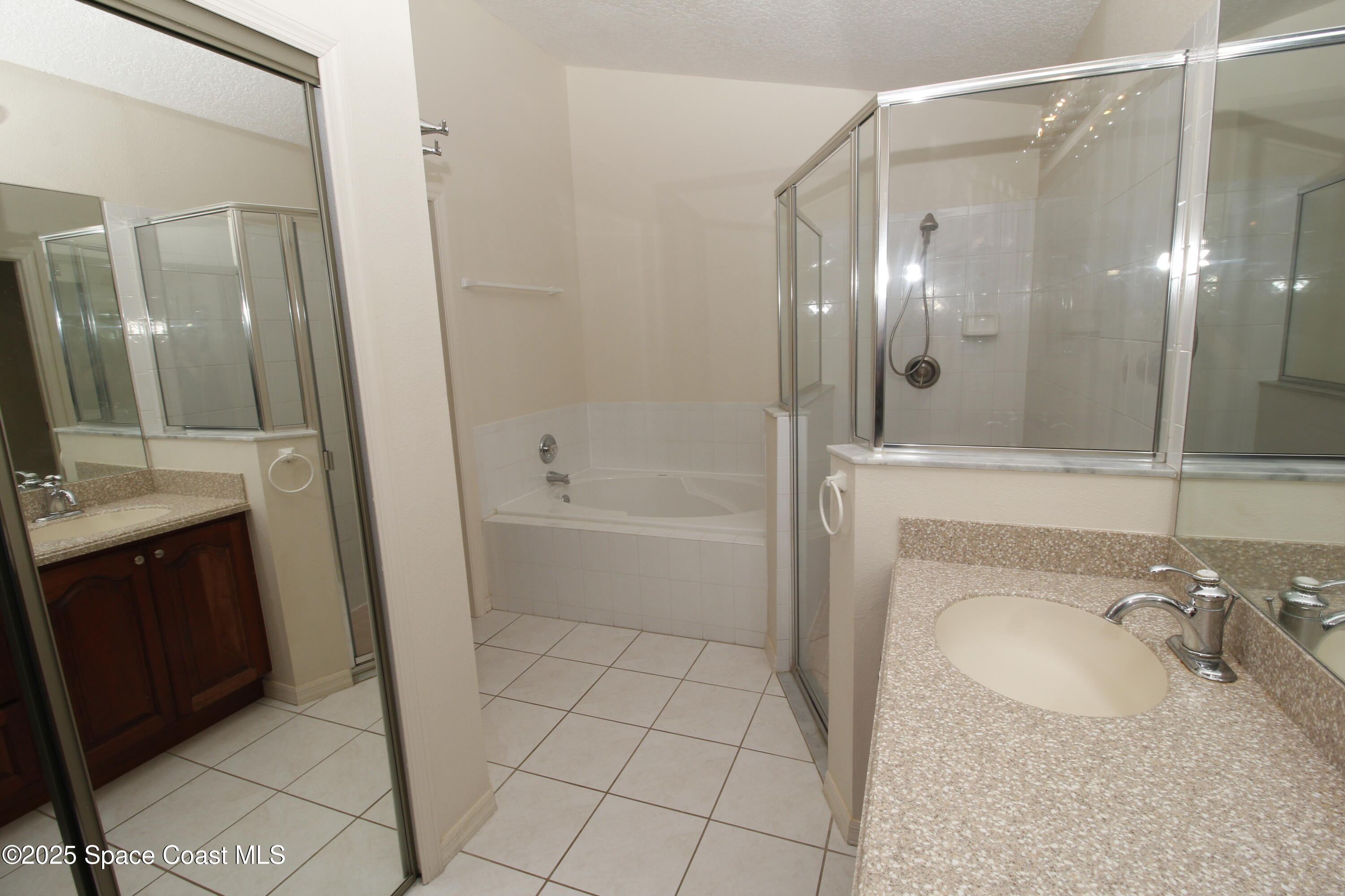 7971 Daventry Drive Melbourne, FL 32940 - Photo 18 of 22 a bathroom with a granite countertop sink a mirror and a bathtub