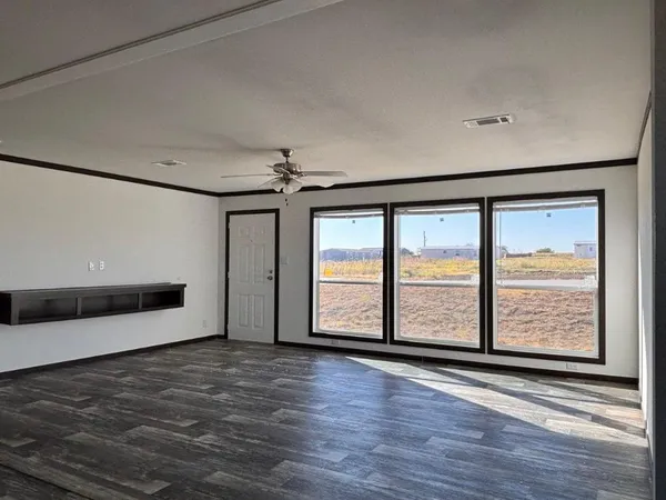 a view of an empty room with window and wooden floor