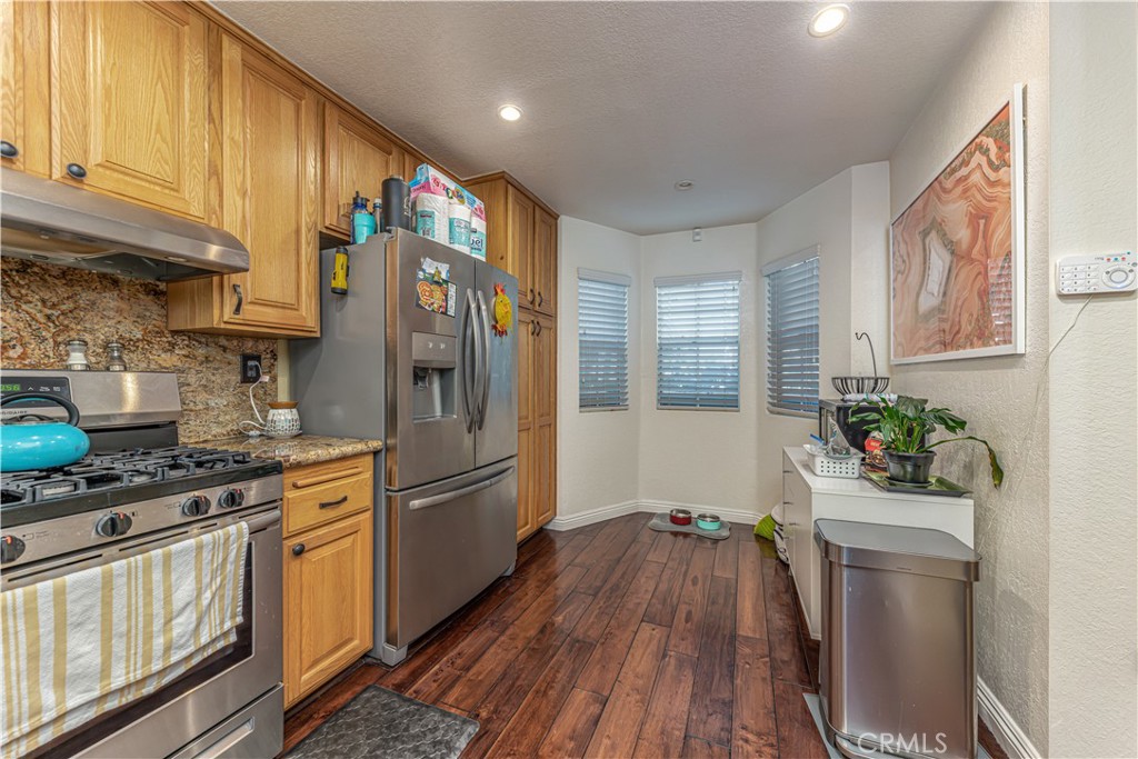 3730 South Bear Street, Unit E Santa Ana, CA 92704 - Photo 26 of 43 a kitchen with stainless steel appliances a refrigerator sink and wooden floor