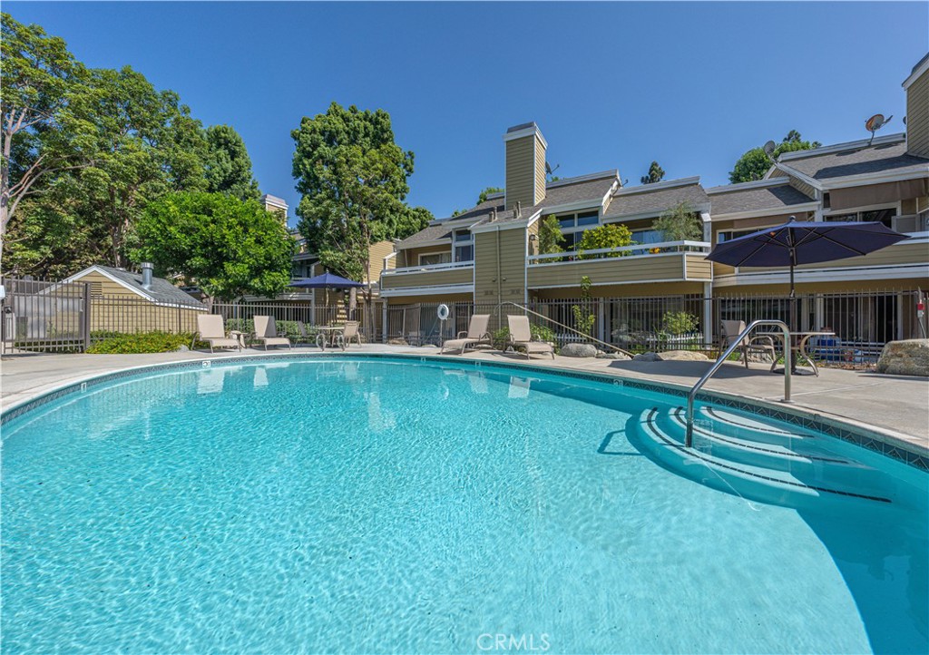 3730 South Bear Street, Unit E Santa Ana, CA 92704 - Photo 35 of 43 a view of a swimming pool with a bench and some trees in the background