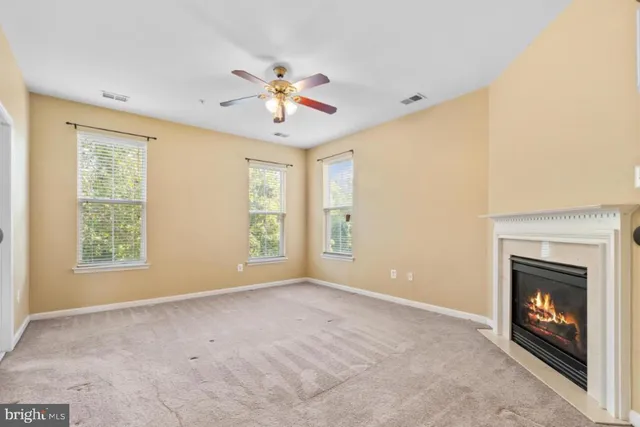 a view of an empty room with chandelier fan and fire place