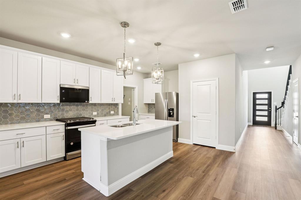 1636 Arches Road Anna, TX 75409 - Photo 5 of 22 a large white kitchen with wooden floor and stainless steel appliances