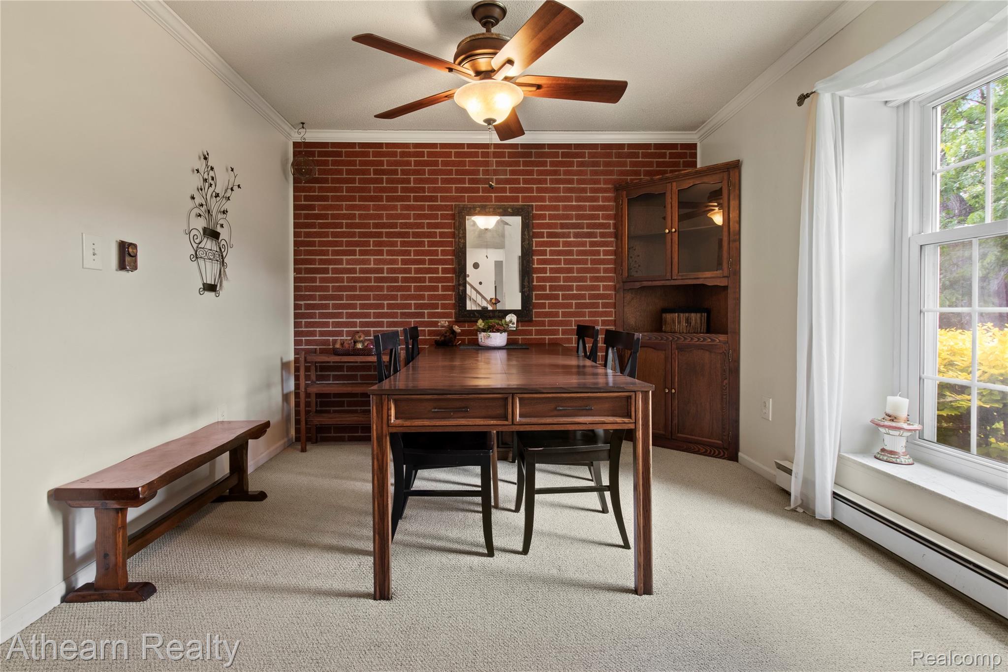 12427 Foley Road Fenton, MI 48430 - Photo 30 of 47 Dining area featuring a brick accent wall, built-in corner cabinet, and a multi-pane window