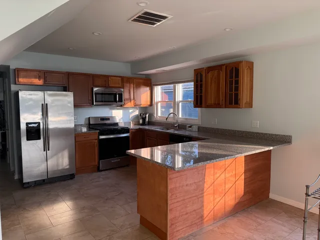 a kitchen with stainless steel appliances granite countertop a sink a stove and a refrigerator