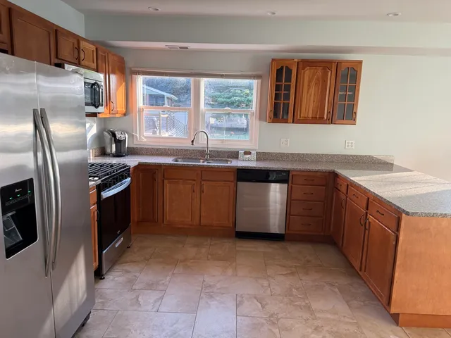 a kitchen with stainless steel appliances granite countertop a sink stove window and refrigerator