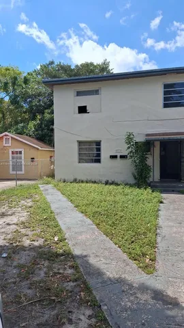a front view of house with yard and trees in the background