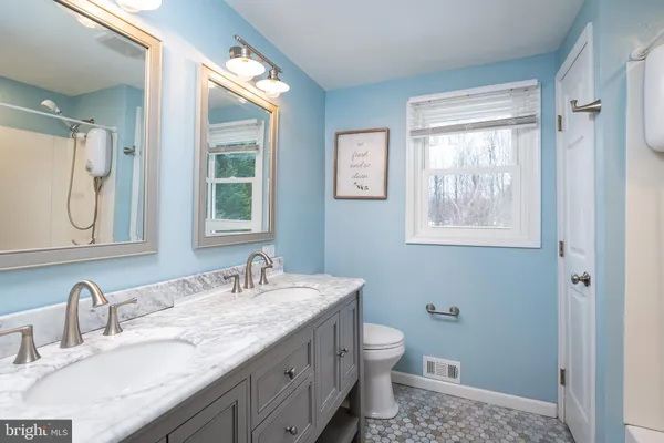 a bathroom with a granite countertop toilet a sink and a mirror