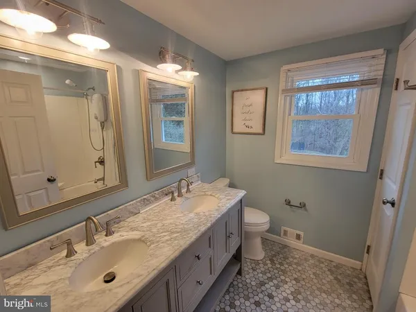 a bathroom with a granite countertop double vanity sink mirror and toilet