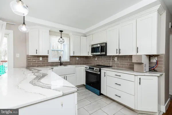 a kitchen with kitchen island granite countertop white cabinets white stainless steel appliances with a sink and dishwasher