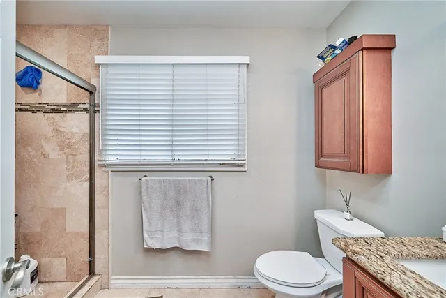 a bathroom with a granite countertop toilet sink and mirror