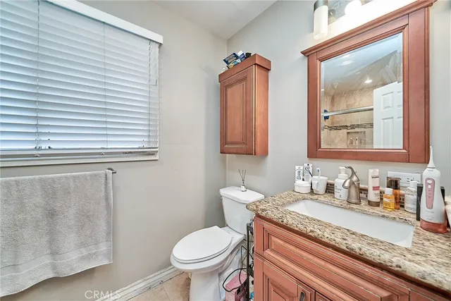 a bathroom with a granite countertop sink and a toilet