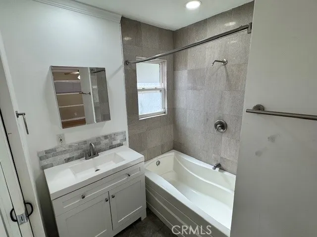 a bathroom with a tub sink shower and mirror