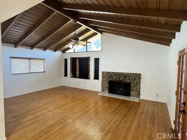a view of an empty room with wooden floor fireplace and a window